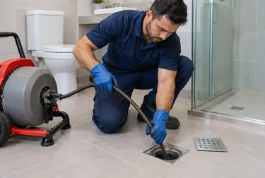 Técnico trabalhando em desentupimento de ralo, utilizando equipamentos específicos.